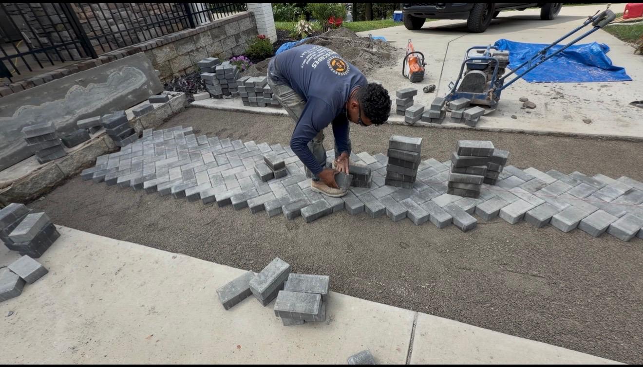 Hand-laying cobble pavers on a compacted base